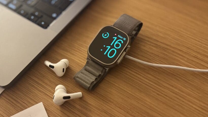 apple watch ultra on charge next to airpods with display showing